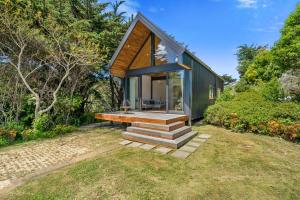 a small green house with a deck and stairs at The Cabin - Wellington Holiday Home in Wellington