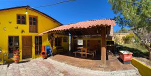 Cabaña San Juanita في Los Lirios: منزل اصفر امامه طاوله