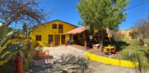 een geel huis met een tafel en stoelen in een tuin bij Cabaña San Juanita in Los Lirios