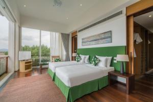 a bedroom with two beds and a large window at The Chava Resort in Surin Beach