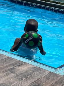 un niño en una piscina sosteniendo una pelota de fútbol en Mikocheni smart apartment en Dar es Salaam