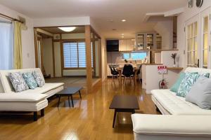 東川町にあるKitamachi Homeのリビングルーム(白いソファ2台付)、キッチンが備わります。