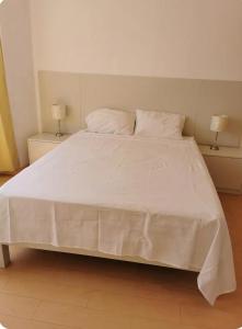 a large white bed with two lamps on two tables at Departamento vista al mar in Ilo