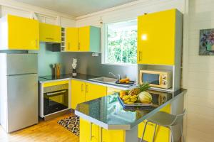 - une cuisine avec des armoires jaunes et un bol de fruits sur un comptoir dans l'établissement Bord de Rivière & Piscine Privée - TiKaz Twopikal, à Sainte-Rose