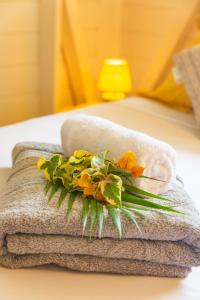 - une pile de serviettes et de fleurs sur le lit dans l'établissement Bord de Rivière & Piscine Privée - TiKaz Twopikal, à Sainte-Rose