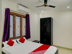 a bedroom with a bed with red pillows and a black cabinet at Flagship Hotel The Guest Land in Visakhapatnam