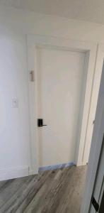 ein leeres Zimmer mit einer weißen Tür und einem Holzboden in der Unterkunft Cozy in Regina