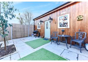 a patio with a table and chairs and a building at Charming Log Cabin with Hot Tub & Grill in London
