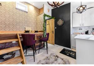 a kitchen with a table and two purple chairs at Charming Log Cabin with Hot Tub & Grill in London