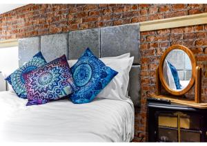 1 dormitorio con cama con almohadas y espejo en Charming Log Cabin with Hot Tub & Grill en Londres