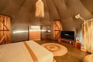 a bedroom with a bed and a television and a chandelier at Domes and Dreams Lio Glamping in El Nido