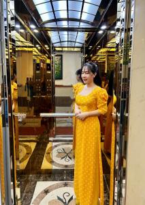 Una mujer con un vestido amarillo parada en una ventana en Gia Hân Hotel en Ho Chi Minh