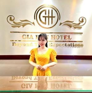 una mujer con un vestido amarillo parada frente a un cartel en Gia Hân Hotel, en Ho Chi Minh