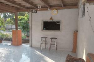 un patio con 2 taburetes y TV en la pared en OYO Life 93015 Kos Anto en Pawenang