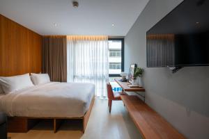 a bedroom with a bed and a desk and a television at Woodstory Boutique Hotel in Bangkok