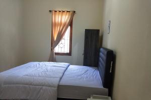 um quarto com uma cama e uma janela em OYO Life 93257 Kos Anugerah em Mataram