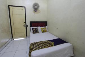 a small bedroom with a bed with yellow and blue pillows at OYO Life 93260 Bale Kosan in Tanjung