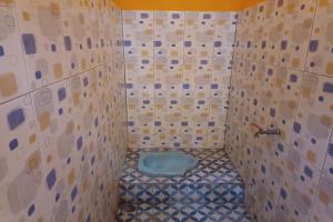a bathroom with a blue toilet in a tiled wall at OYO Life 93260 Bale Kosan in Tanjung