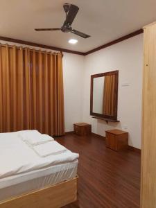 Schlafzimmer mit einem Bett und einem Wandspiegel in der Unterkunft Oi Beach in Maamigili