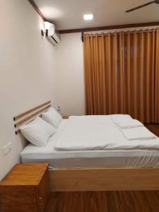 a bedroom with a large bed with white sheets at Oi Beach in Maamigili