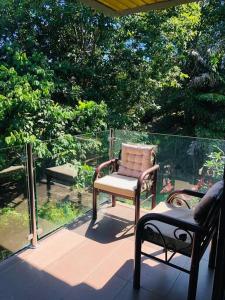 einen Stuhl und einen Stuhl auf einer Veranda mit Bäumen in der Unterkunft 2 bedrooms Apartment in Pantai Cenang