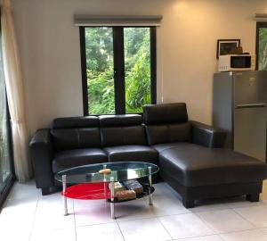 ein Wohnzimmer mit einem schwarzen Sofa und einem Glastisch in der Unterkunft 2 bedrooms Apartment in Pantai Cenang