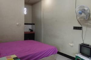 a bedroom with a purple bed and a fan at OYO Life 93403 Penginapan Adinda in Tjakranegara