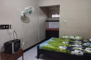 a bedroom with a bed and a fan and a television at OYO Life 93403 Penginapan Adinda in Tjakranegara