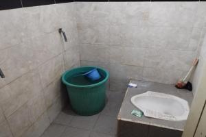 a bathroom with a green trash can and a sink at OYO Life 93403 Penginapan Adinda in Tjakranegara