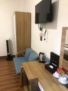 a living room with a blue couch and a tv at Tommy hotel khe sanh dalat in Da Lat