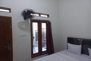 a bedroom with a bed and a window with a fan at SPOT ON 93553 Juan Kostel in Banyumas