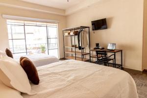 - une chambre avec 2 lits, un bureau et une télévision dans l'établissement Hotel Casa María Teresa, à León