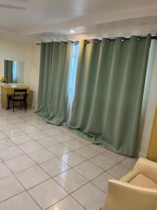 sala de estar con cortinas verdes y mesa en Mikocheni smart apartment, en Dar es Salaam