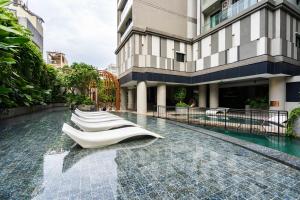 una piscina de hotel con sillas blancas frente a un edificio en Zenity 3BR Condo: Luxury and Comfort in Quận 1, en Ho Chi Minh