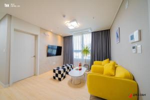 sala de estar con sofá amarillo y mesa en Eunhasu D&M Residence Haetsal 1 en Daejeon