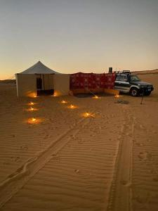 a tent and a car in the desert with lights at Nuba falcon in Aswan