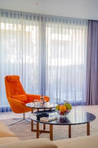 The Five Villas & Resort Quangnam - Danang في هوي ان: غرفة معيشة مع كرسي برتقالي وطاولة زجاجية