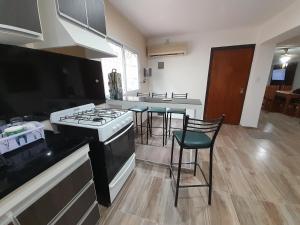 a kitchen with a stove and some chairs in it at Casa Blend in Las Heras