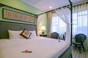 um quarto com uma cama com uma colcha branca em Hoi An Town Home Resort em Hoi An