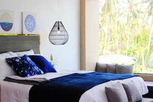 Un dormitorio con una cama con almohadas azules y una ventana en The Willow Phangan, en Ko Pha Ngan