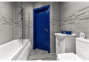 a bathroom with a blue door and a tub and a toilet at Palatial Style House Secs to Lovely River Walk in London