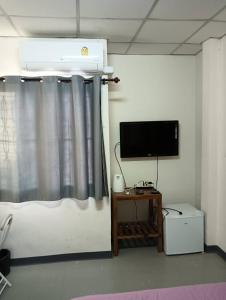 a bedroom with a bed with a television and a table at ครัวบ้านเอื้อ ห้องพักรายวัน in Ban Thung Sawang