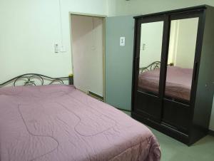 a bedroom with a pink bed and a mirror at ครัวบ้านเอื้อ ห้องพักรายวัน in Ban Thung Sawang