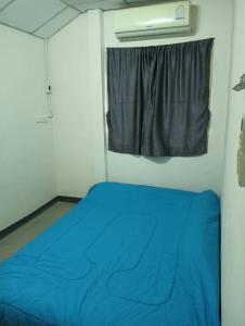 Habitación con cama azul y ventana en ครัวบ้านเอื้อ ห้องพักรายวัน en Ban Thung Sawang