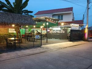 un restaurante con mesas y sillas frente a un edificio en ครัวบ้านเอื้อ ห้องพักรายวัน en Ban Thung Sawang