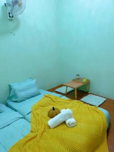 uma cama com um cobertor amarelo e duas toalhas enroladas em C & L Home 002 em Keluang