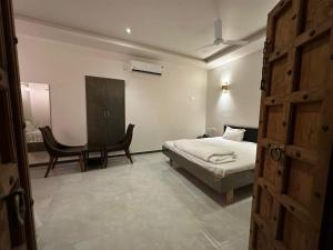 a bedroom with a bed and a desk and a chair at Hotel Surbhi in Mundra