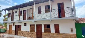 a house with wooden doors and a balcony at Mary Suítes in Lençóis