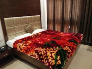 a bed with a red and orange blanket on it at Hotel Mahal Inn,Amritsar in Amritsar