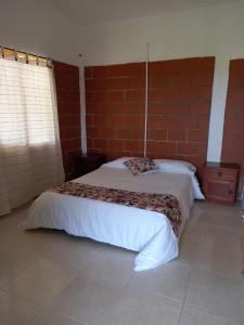 a bedroom with a bed and a brick wall at LA RIVERA HOSTERIA CAMPESTRE in Villamaría